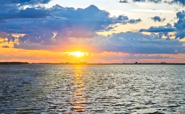 Vue sur le coucher du soleil sur le lac avec chemin de la lumière du soleil. Deux clichés piquent l'image.