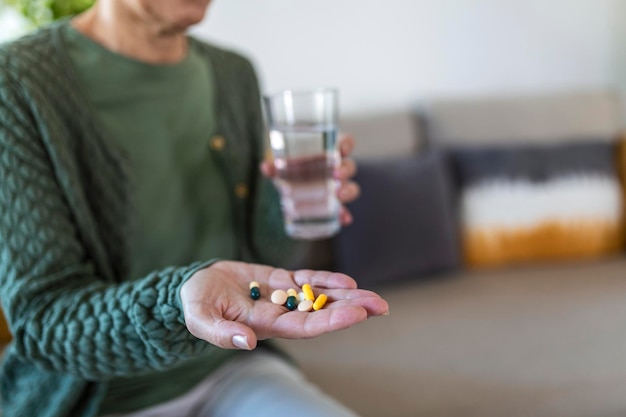 Vue coupée d'une femme âgée malade et malade tenant différentes pilules sur la paume de la main montrant un prepar médical sur la caméra