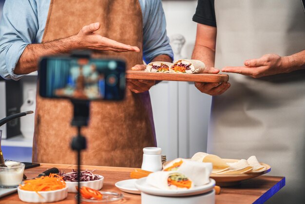 Vue coupée d'influenceurs de chefs présentant des rouleaux de salade frais vendables