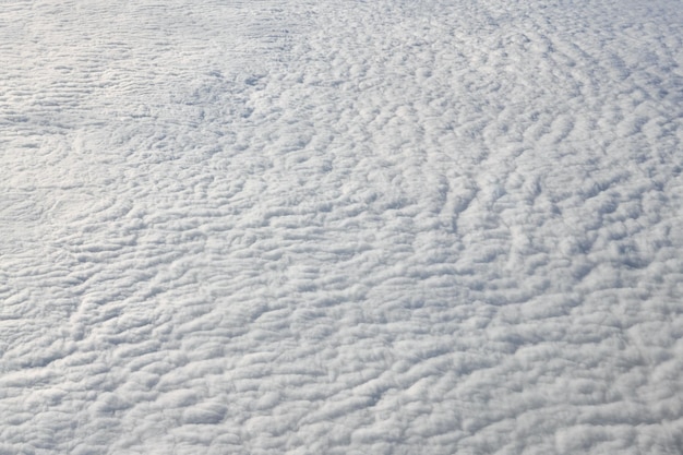 Vue à couper le souffle sur les nuages depuis la fenêtre de l'avion épais nuages bleus blancs ressemble à de la mousse souple
