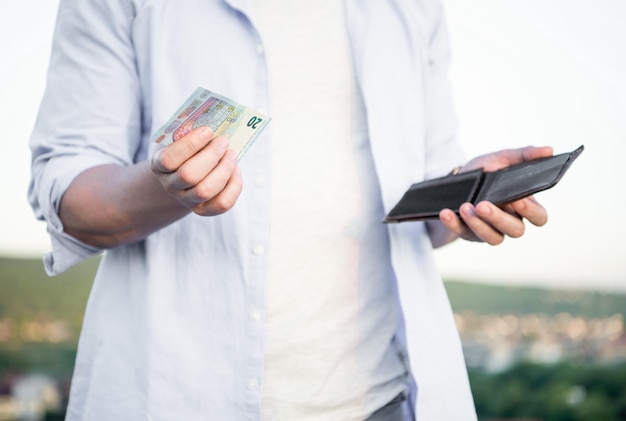 Vue sur les cultures de l'homme tenant des billets de banque et un portefeuille dans les mains à l'extérieur