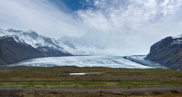 Vue depuis l'autoroute pendant un voyage en voiture en Islande Paysage islandais spectaculaire avec des hameaux naturels pittoresques montagnes côte de l'océan fjords champs nuages glaciers cascades