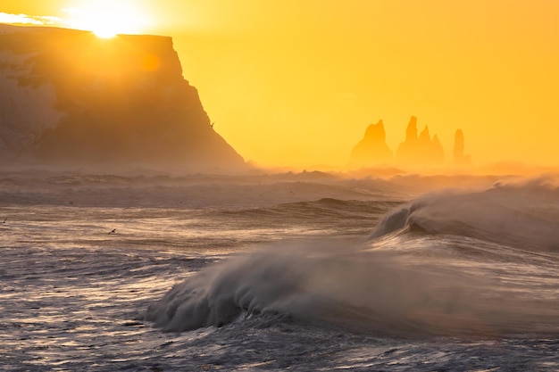 Vue depuis le cap Dyrholaey sur la plage de Reynisfjara et les piles de mer de basalte de Reynisdrangar Islande Lever de soleil orageux