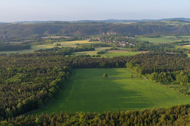 Vue depuis la falaise Paysage pittoresque avec des maisons confortables, des prés verts et des arbres Beau paysage de montagne Suisse saxonne Lilienstein lever du soleil longues ombres à travers les champs