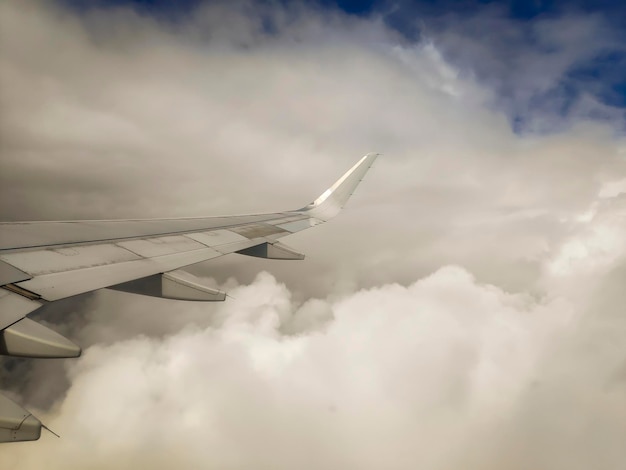 Vue depuis la fenêtre de l'aile d'un avion volant au-dessus des nuages et d'un ciel bleu