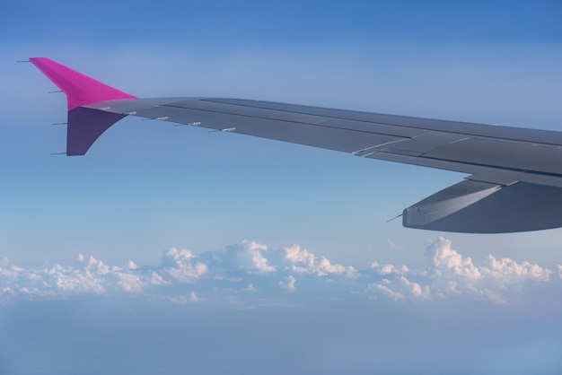 Vue depuis la fenêtre de l'avion Aile d'un avion volant au-dessus des nuages avec un ciel bleu