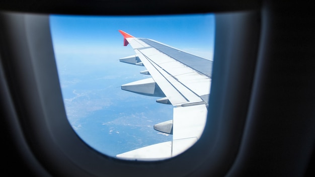 Vue depuis la fenêtre de l'avion sur l'aile et la terre.