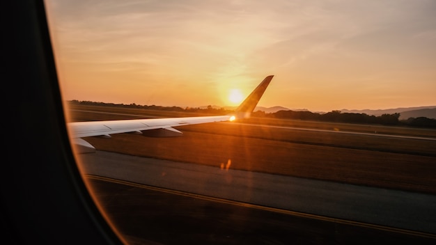 Vue depuis la fenêtre de l'avion Voir les ailes d'un avion avec un coucher de soleil à l'heure d'or.