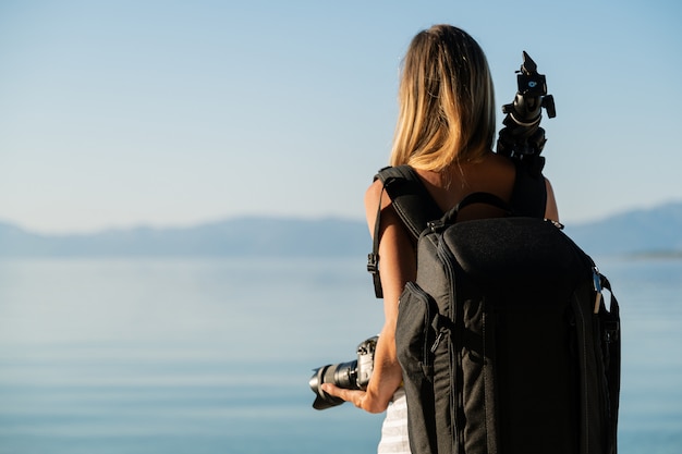 Vue de derrière de la photographe professionnelle avec sac photo sur le dos