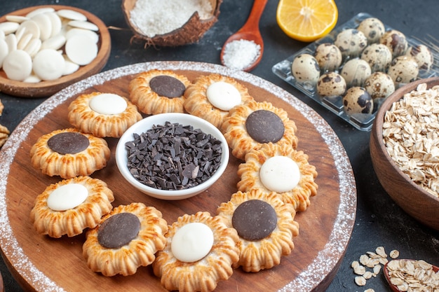 vue de dessous biscuits au chocolat et chocolat noir sur planche de bois oeufs de caille dans des bols viole avec avoine et bonbons sur table