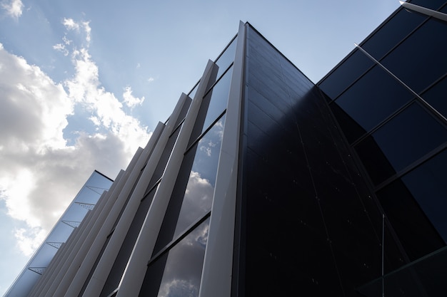 Vue de dessous du bâtiment nouveau et moderne avec des murs en verre reflétant le ciel