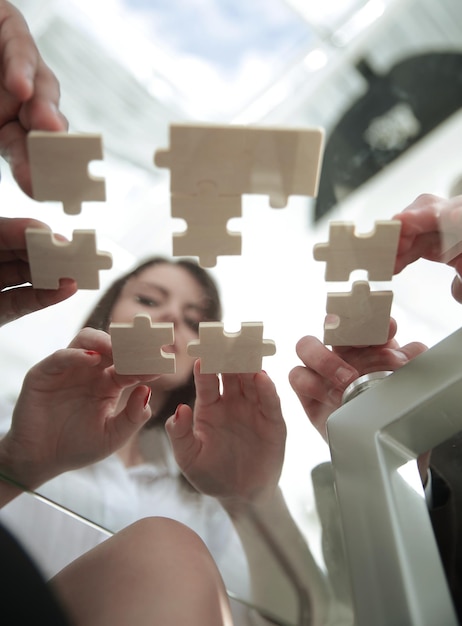 Vue de dessous équipe commerciale pliant des pièces de puzzle