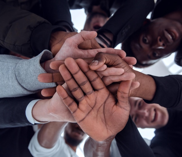 Vue de dessous un groupe de jeunes divers joignant leurs mains ensemble