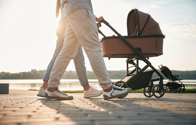 Photo vue de dessous des jambes un jeune couple avec une poussette se promène ensemble