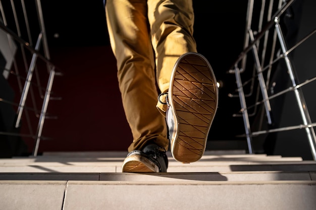 Vue de dessous d'un jeune homme descendant les escaliers en pantalon jaune