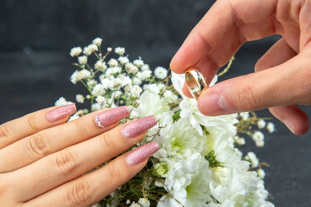 Vue de dessous proposition de mariage concept mains de l'homme plaçant l'anneau de mariage sur les fleurs de mariage blanc main femme