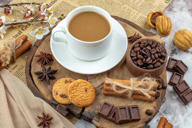 vue de dessous tasse de biscuits au café bol avec grains de café torréfiés bâtons de cannelle chocolat anis sur planche de bois sur table