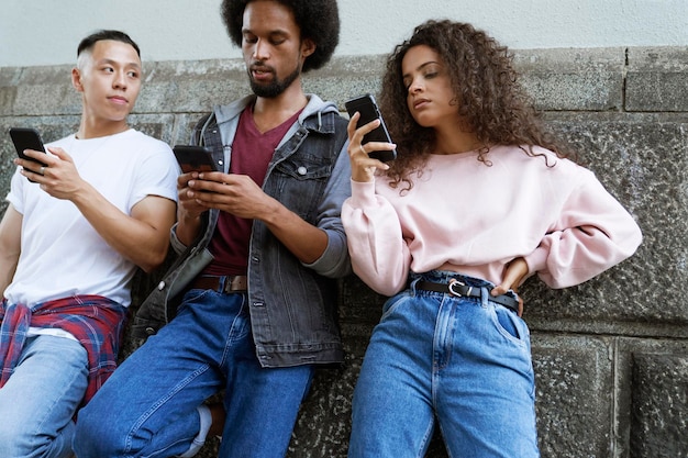 Photo vue de dessous de trois jeunes debout avec des téléphones portables