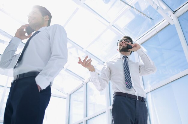 Vue de dessousdes gens d'affaires parlant sur leur téléphone portable au bureaule concept de communication