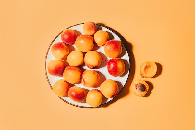 Vue de dessus des abricots dans une assiette ronde sur fond orange