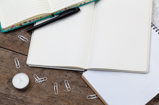 Vue de dessus sur les accessoires stylo, carnet, trombone, bougie sur un fond en bois