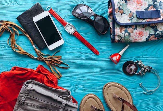 Vue de dessus des accessoires de voyage féminins sur fond bleu en bois avec copie