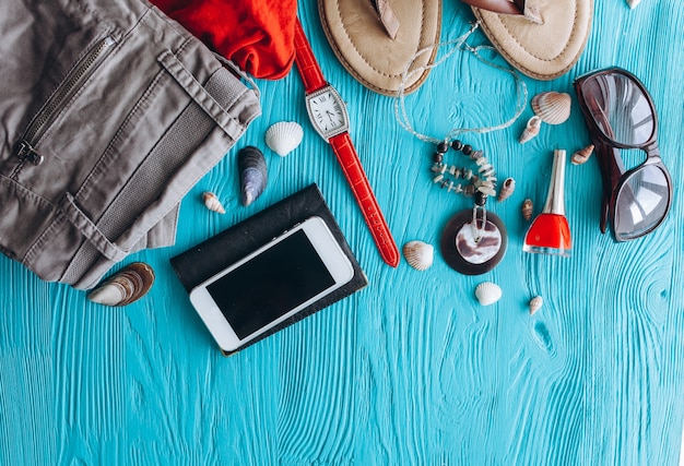 Vue de dessus des accessoires de voyage féminins sur fond bleu en bois avec copie