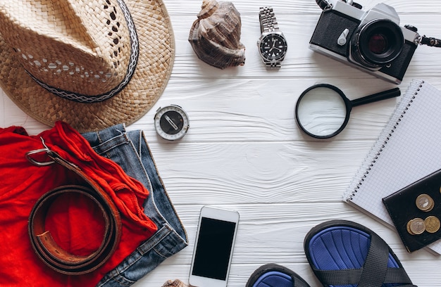 Vue de dessus des accessoires de voyage sur fond de bois blanc avec copie