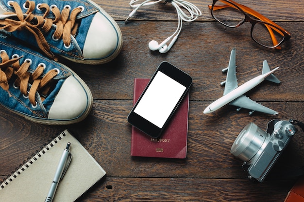 Vue de dessus accessoires Voyage avec téléphone portable, passeport, appareil photo, écouteurs, notepaper, glaases, avion sur table en bois avec copie space.Travel concept.