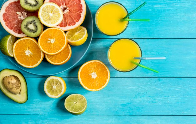 Vue de dessus des agrumes et du jus d'orange fraîchement pressé sur fond bleu