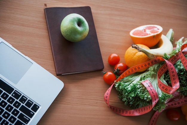 Vue de dessus d'aliments sains, ruban à mesurer et ordinateur portable sur la table. Conception des soins de santé.