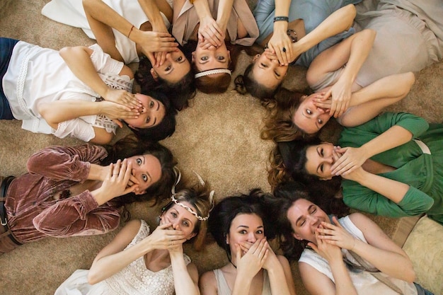 Vue de dessus amies se cachant la bouche par les mains en riant cercle couché relaxant ensemble à henparty