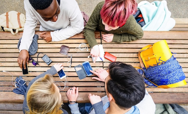 Vue de dessus d'amis multiraciaux utilisant un téléphone intelligent mobile