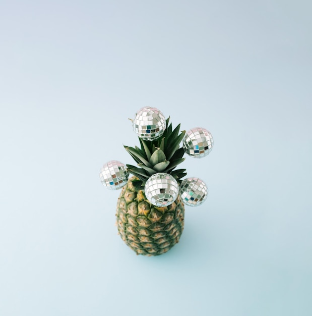 Vue de dessus d'ananas frais avec des boules disco sur les feuilles