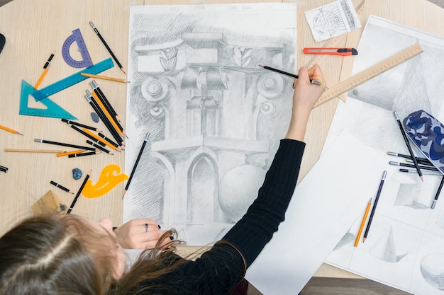 La vue de dessus de l'architecte designer féminin dessine des croquis au crayon sur du papier blanc.