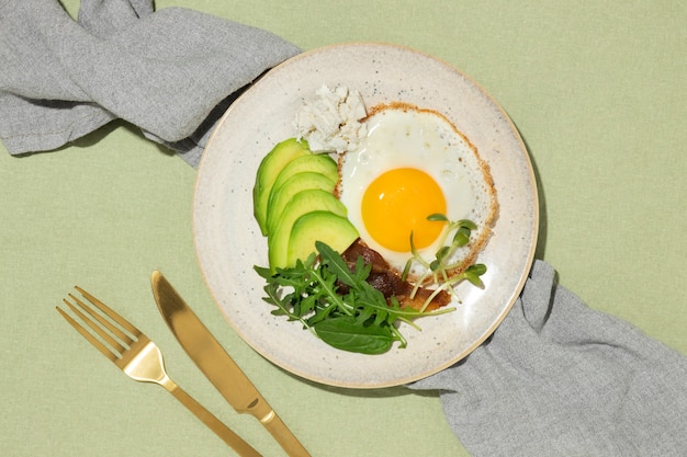 Vue de dessus de l'assiette avec des aliments diététiques céto et une fourchette et un couteau dorés