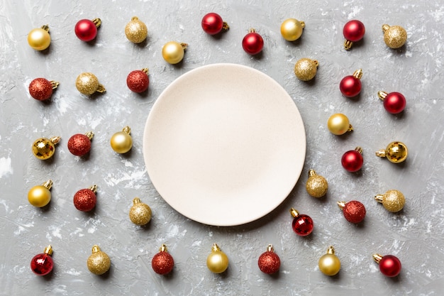 Vue de dessus d'une assiette de fête avec des boules rouges et dorées sur du ciment,