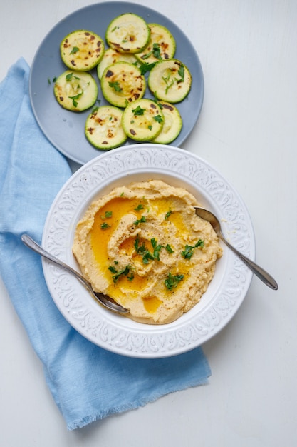 Vue de dessus d'une assiette de houmous crémeux maison saine sur fond gris