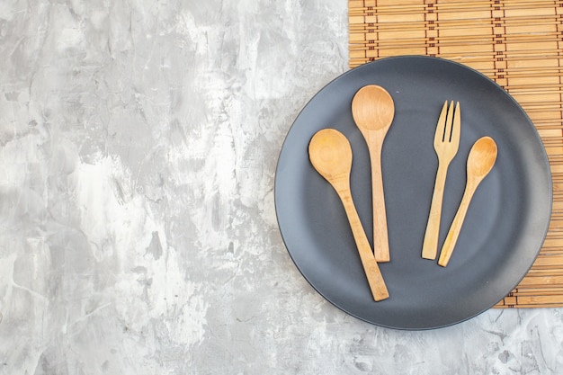 Vue de dessus assiette sombre avec des cuillères en bois sur une surface claire mesdames de cuisine alimentaire couleur horizontale repas verre féminité