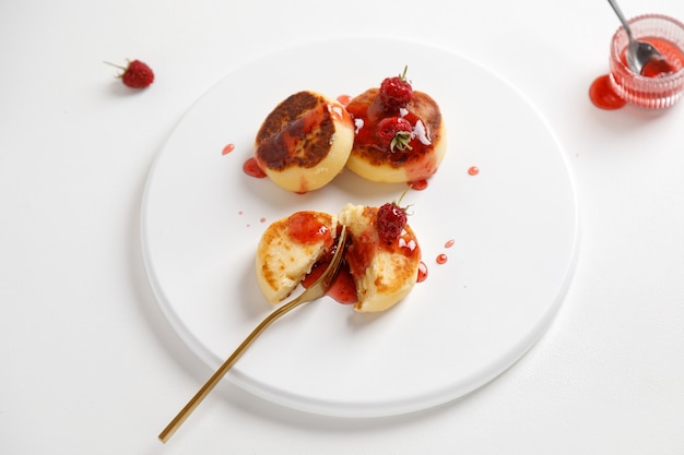 Vue de dessus de l'assiette avec syrniki de crêpes au fromage ou gâteaux au fromage avec du jus sur fond blanc