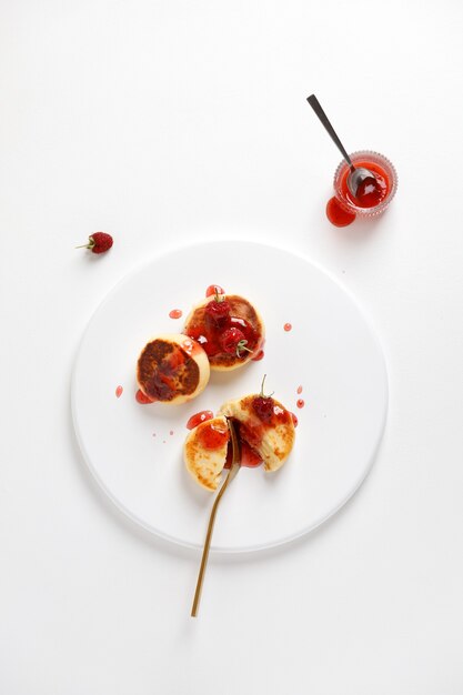 Vue de dessus de l'assiette avec syrniki de crêpes au fromage ou gâteaux au fromage avec du jus sur fond blanc