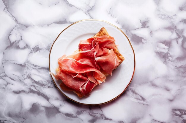 Vue de dessus d'une assiette avec un toast de jambon Serrano minimaliste