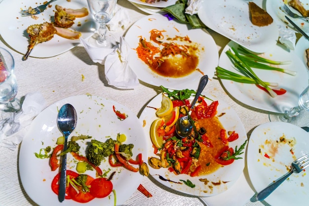 Vue de dessus des assiettes et des verres sales après un repas sur la table du restaurant Les restes de nourriture sur la vaisselle sale après le dîner