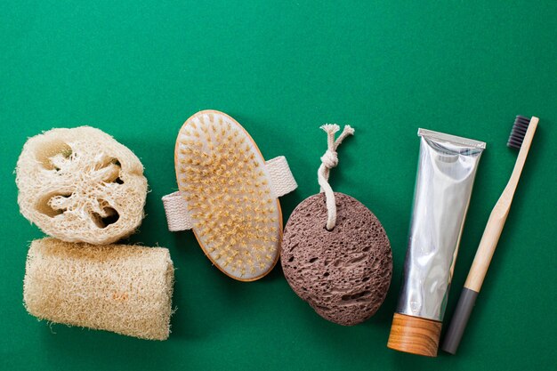 Vue de dessus assortiment de produits d'hygiène durables pour la vie dans un concept minimaliste Luffah brosse brosse à dents pâte et pierre ponce sur fond vert