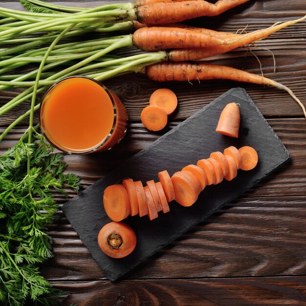 Photo vue de dessus au jus de carotte végétarien bio frais sur une table de cuisine en bois