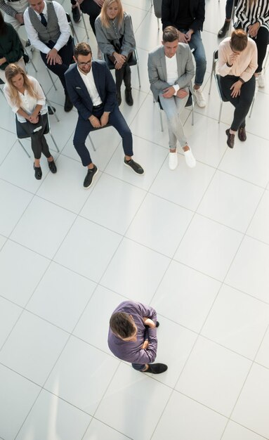 Vue de dessus des auditeurs applaudissant le conférencier lors d'un séminaire d'entreprise