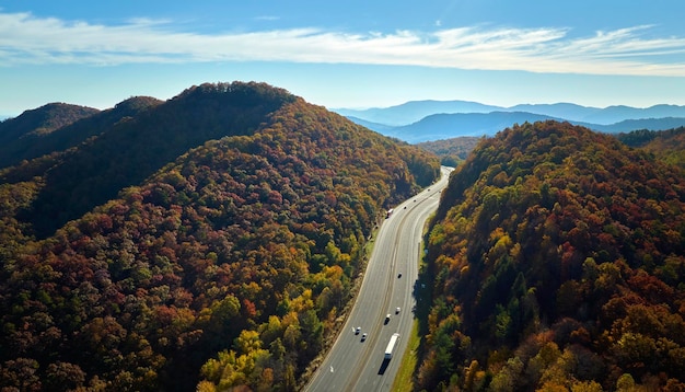 Vue de dessus de l'autoroute I40 en Caroline du Nord menant à Asheville à travers les Appalaches avec des bois d'automne jaunes et des camions et des voitures en mouvement rapide Concept de transport inter-États