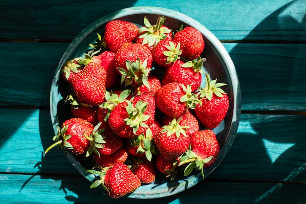 Vue de dessus aux fraises fraîches dans la plaque verte sur une table en bois verte