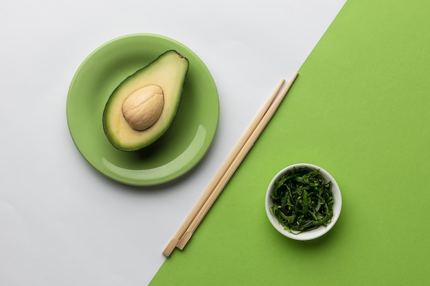 Vue de dessus de l'avocat avec bol de légumes verts et baguettes