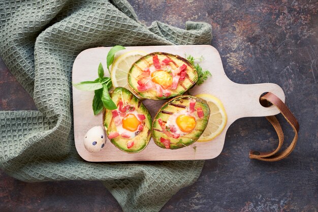 Vue de dessus sur les bateaux d'avocat grillés avec bacon et œufs de caille